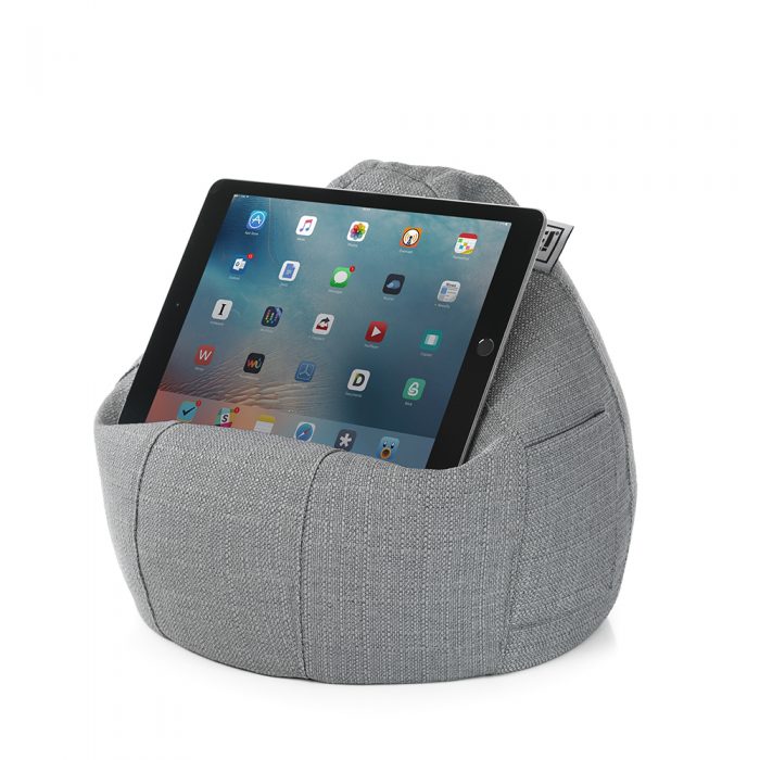 A tablet sits on a grey linen look iCrib iPad rest holder stand cushion bean bag. A storage pocket is visible.